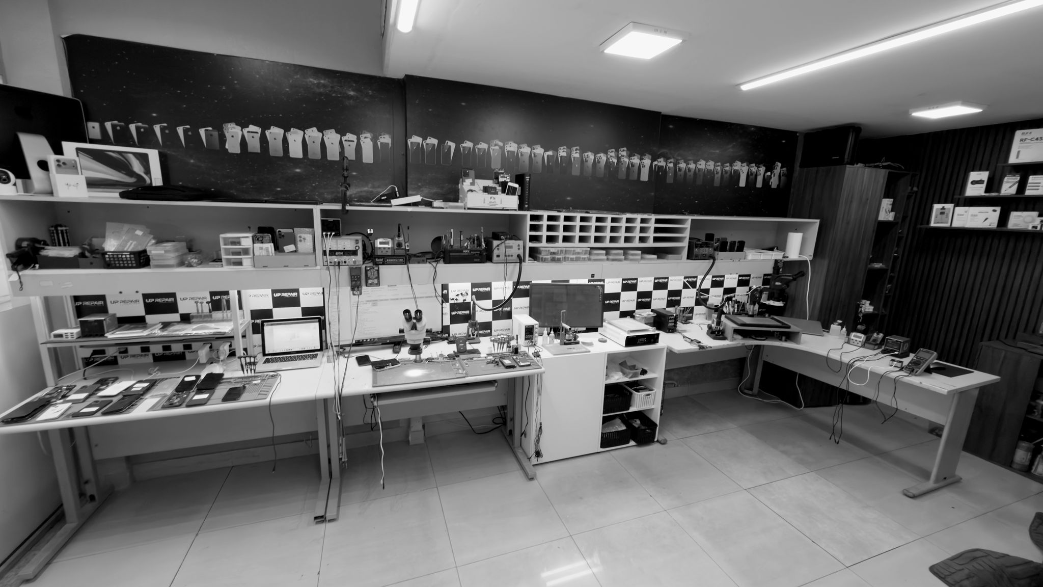 Bancada técnica do laboratório Uprepair com microscópios trinoculares e estações de soldagem profissional